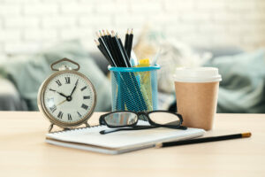 Classic vintage alarm clock and coffee cup on wooden background