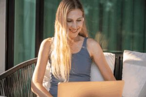 Mulher sentada em cadeira olhando apra o notebook