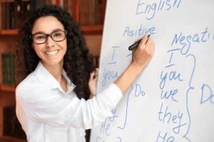 Melhor curso de inglês para a Austrália Mulher sorridente escrevendo em um quadro branco